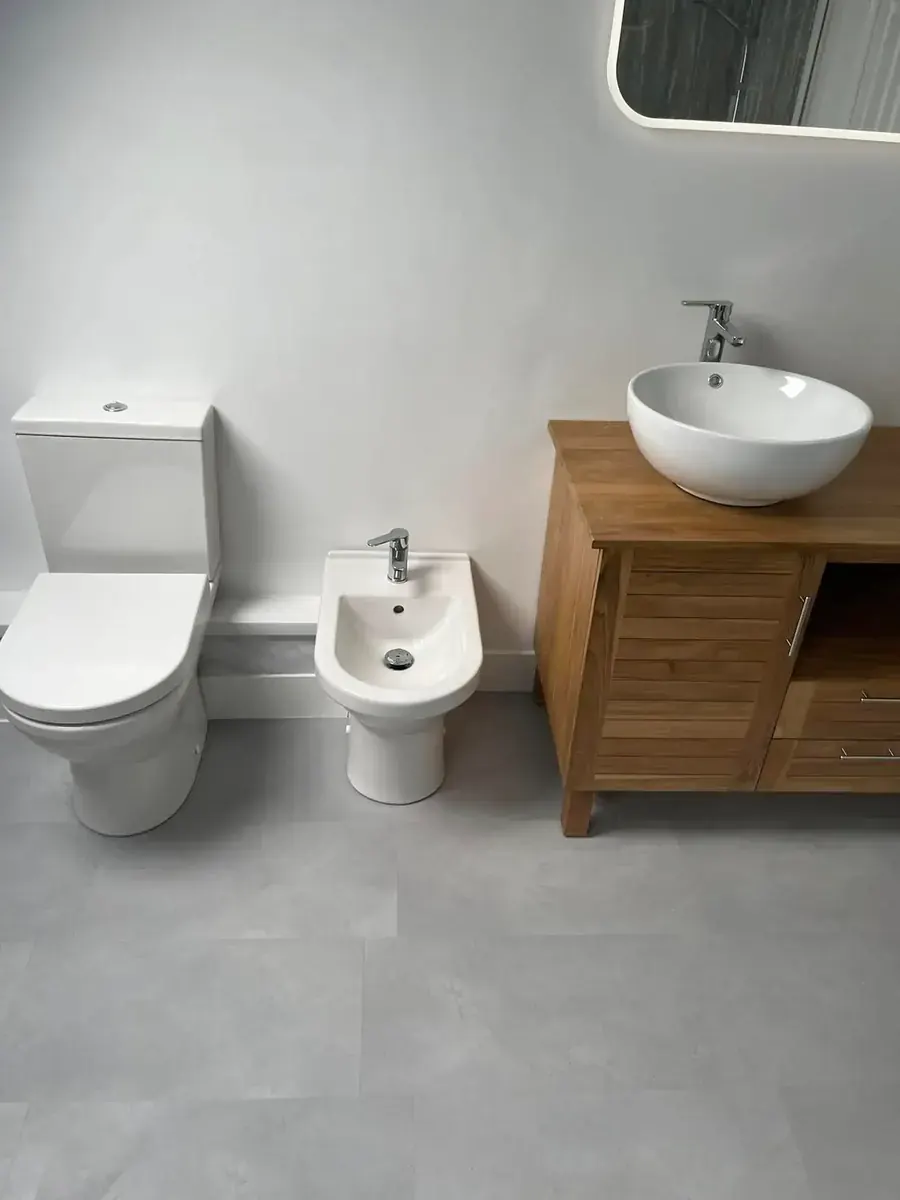 Bathroom installation in South Wales — teak vanity unit, countertop basin, bidet and grey tiled floor