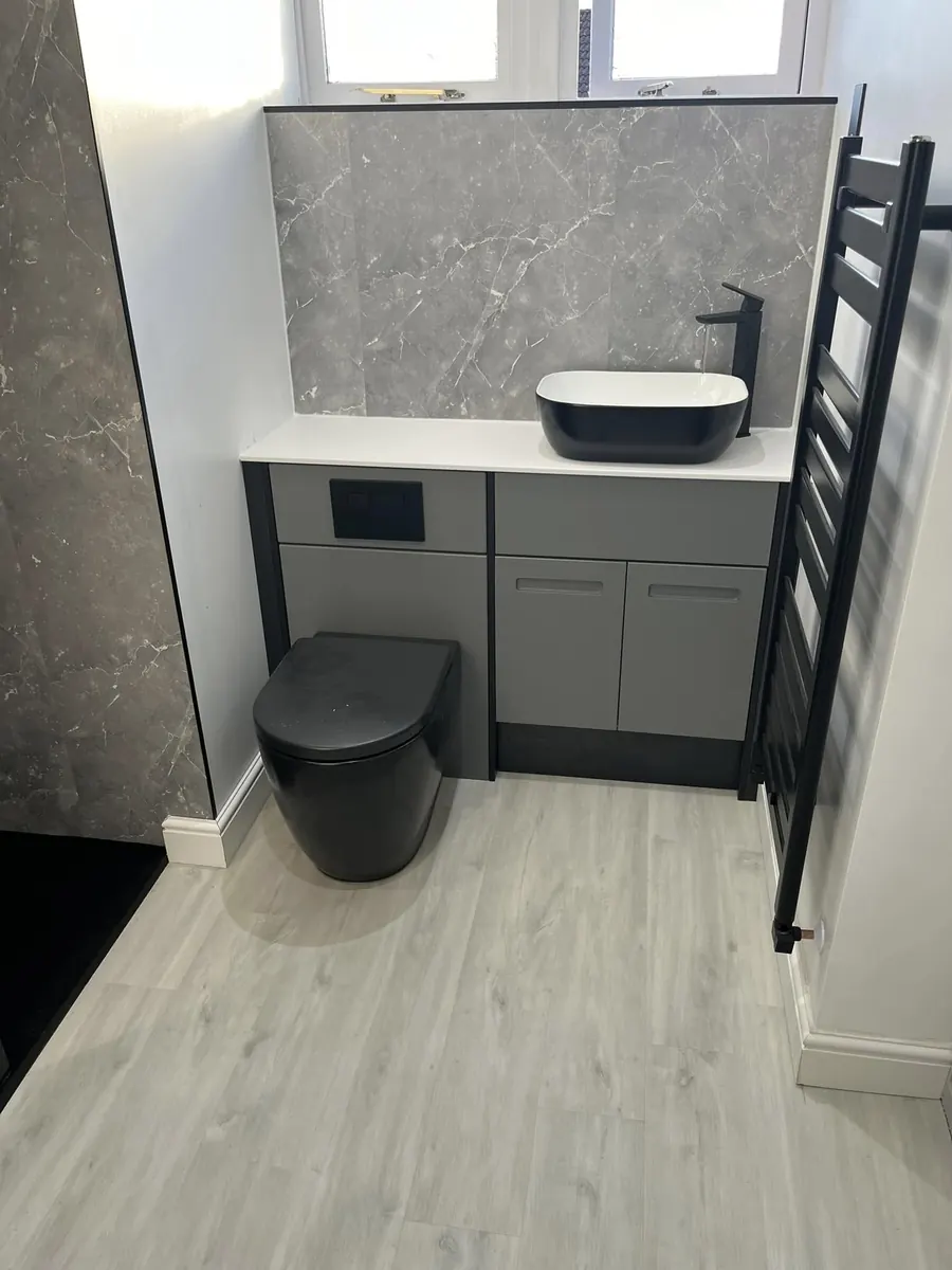Matt grey fitted furniture with black countertop basin, black tall tap and black heated towel rail