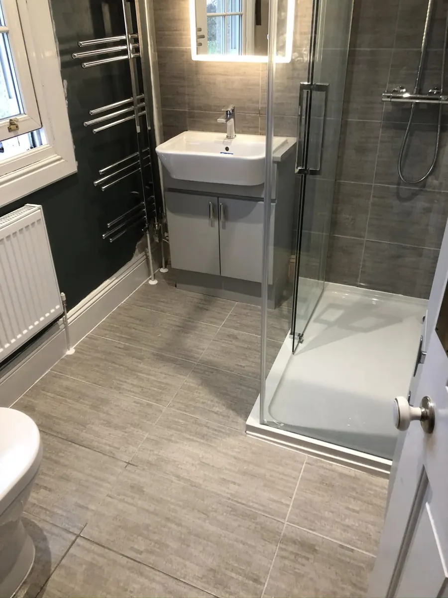 Grey shower room refit with corner enclosure, vanity basin unit and chrome heated towel rails