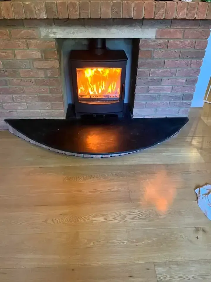 HETAS solid fuel installation — wood burning stove on a curved slate hearth in a brick fireplace